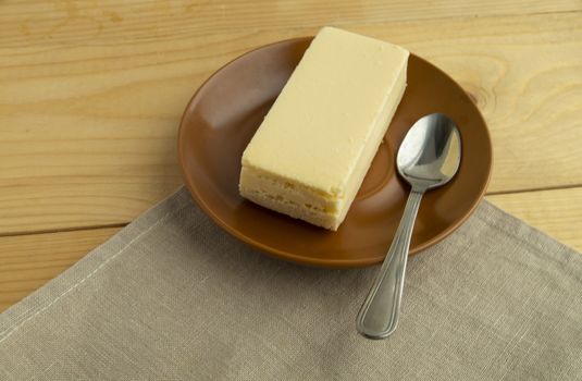 A piece of classic new York vanilla cheesecake on a light wooden background and linen napkin, close-up