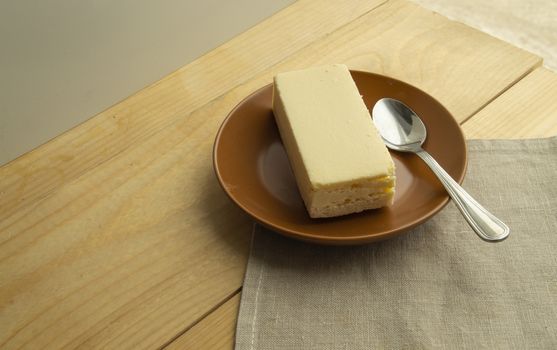 A piece of classic new York vanilla cheesecake on a light wooden background and linen napkin, close-up