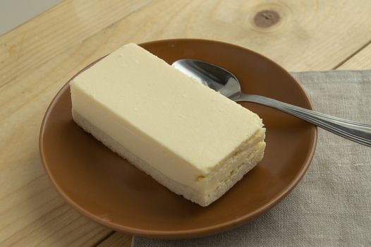 A piece of classic new York vanilla cheesecake on a light wooden background and linen napkin, close-up