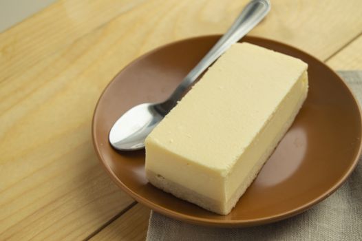 A piece of classic new York vanilla cheesecake on a light wooden background and linen napkin, close-up