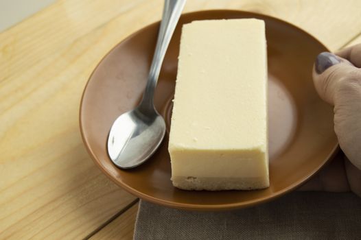 A piece of classic new York vanilla cheesecake on a light wooden background and linen napkin, close-up