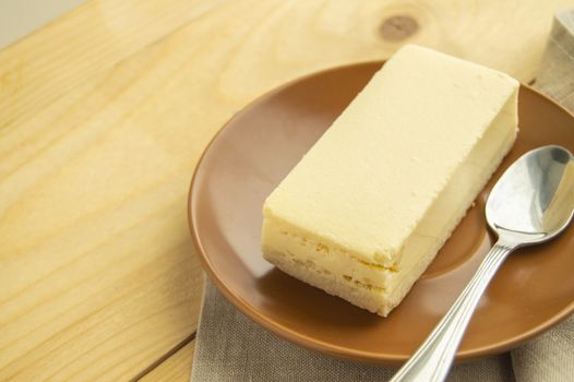 A piece of classic new York vanilla cheesecake on a light wooden background and linen napkin, close-up