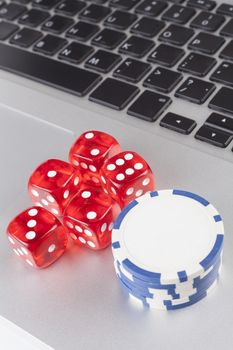 Red casino dices with chips on silver laptop 