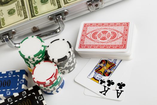 Casin ochips with briefcase full with dollars in the backgrouns and playing cards isolated on white