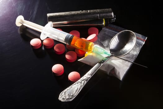Durgs with spoon and syringe on dark background with side ightning