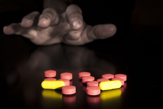 Hand Grabin colored medicine on black table with reflection