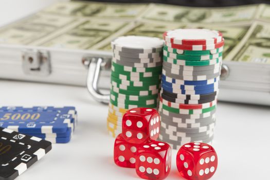 Casino chips with red dice close-up  and briefcase full with dollars isolated on white background