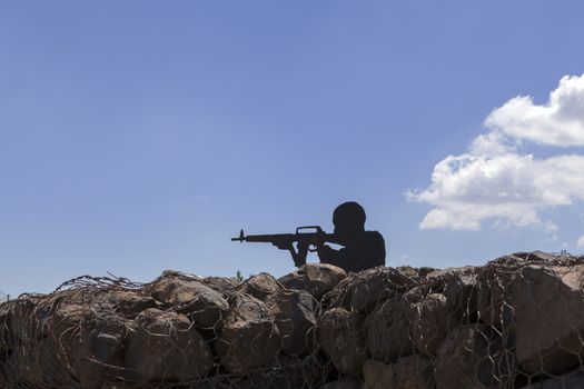 Soldier silhouette with blue sky in the background and rock reinforments in the foreground