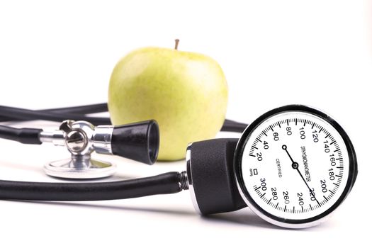 Black sthethoscope and sphygmamanometer with green apple in the background isolated on white