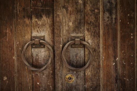 Old rusty  wooden double sided gate with round handles close-up
