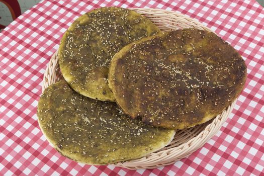 Pita bread with zaatar green middle eastern herb on red table