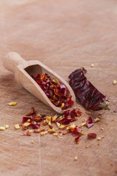 Dry red hot chilli peppers with wooden spoon on brown wood background