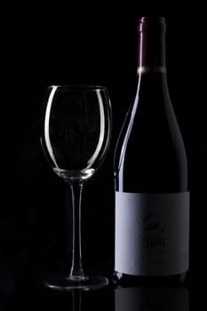 Wine bottle and empty glass silhouette on black background