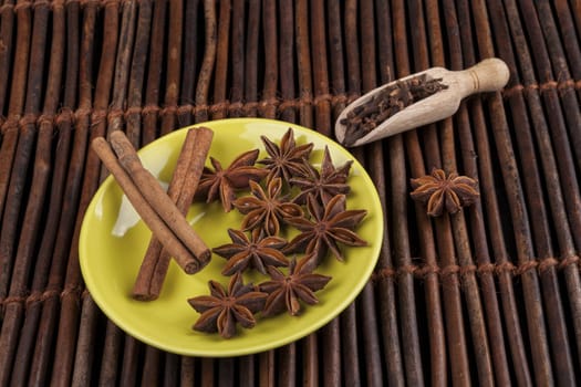 Cinnamon sticks with star shape anis on green plate and wood background