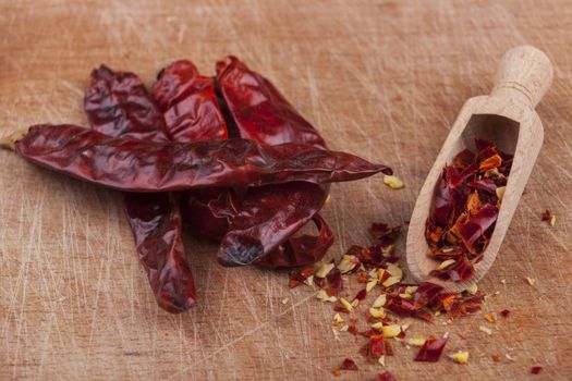 Dry red hot chili peppers with wooden spoon on brown wood background