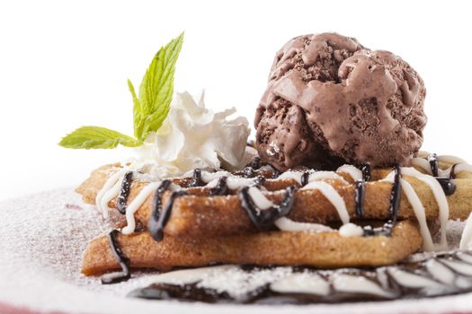 Belgian waffle with chocolate syrup whipped cream and red cherry on red plate
