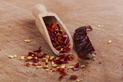 Dry red hot chili peppers with wooden spoon on brown wood background