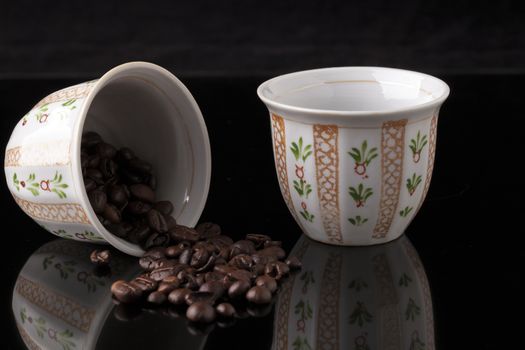 Hand painted traditional arabic coffee cups on black background and coffee  beans with reflection