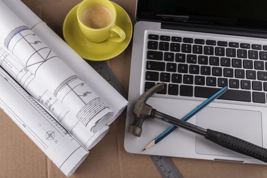 Architectural plans rolled with silver laptop hamer and a pencil