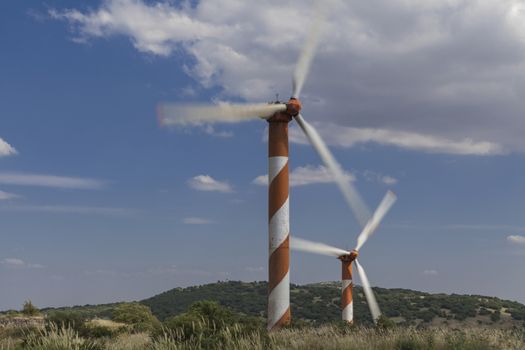 Two Orange windmill with motion  on blue sky background with white clouds