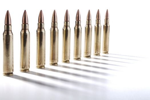 Row of shiny rifle bulets isolated on white with shadows