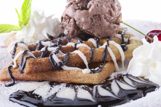 Belgian waffle with chocolate syrup whipped cream and chocolate ice cream with red cherry