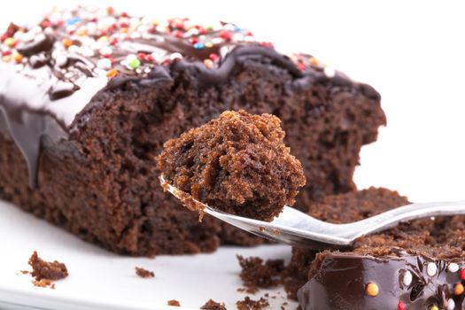 Sweet chocolate cake with colored candy on the top close-up isolated on white