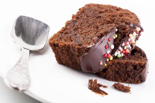 Sweet chocolate cake slice with colored candy on the top  isolated on white