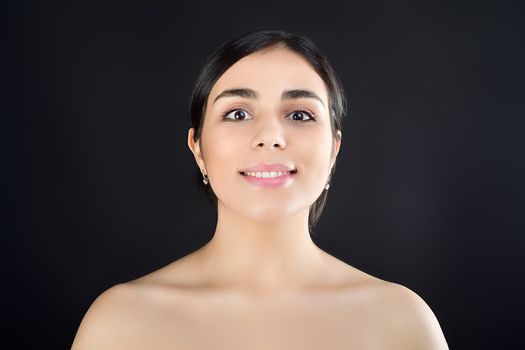 Portrait of a young beautiful girl who smiles and stands on a black background. Studio shooting