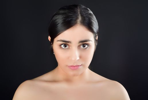 Beauty Portrait of young brunette girl with bare shoulders on black background