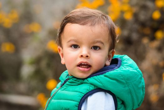 Outdoor portrait of mixed raced toddler in a garden, out of focus marigold flowers in the background.