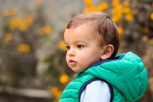 Outdoor portrait of mixed raced toddler in a garden, out of focus marigold flowers in the background.