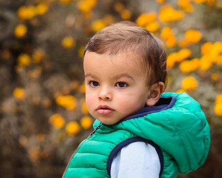 Outdoor portrait of mixed raced toddler in a garden, out of focus marigold flowers in the background.