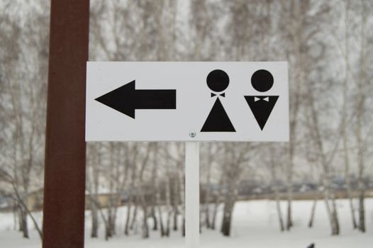 A pointer to a public toilet and the sign of a man and a woman. Hygiene in the Park, outdoor.