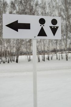 A pointer to a public toilet and the sign of a man and a woman. Hygiene in the Park, open vertical frame