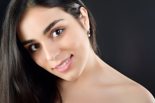 Portrait of a beautiful girl who stands in the studio and smiles at the camera in the studio on a black background