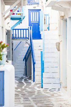 traditional narrow street in Mykonos with blue doors and white walls