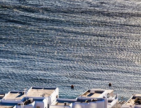 panoramic view of the Mykonos town harbor with famous windmills from the above hills on a sunny summer day, Mykonos, Cyclades, Greece