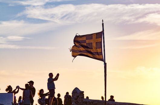 silhouettes of people taking pictures with smartphones and Greek flag