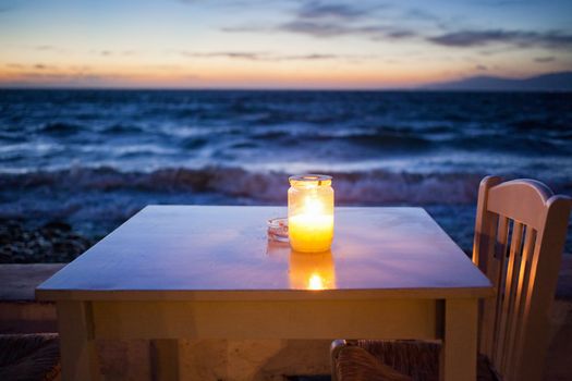 romantic table with burning candle by the sea at night