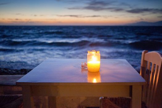 romantic table with burning candle by the sea at night