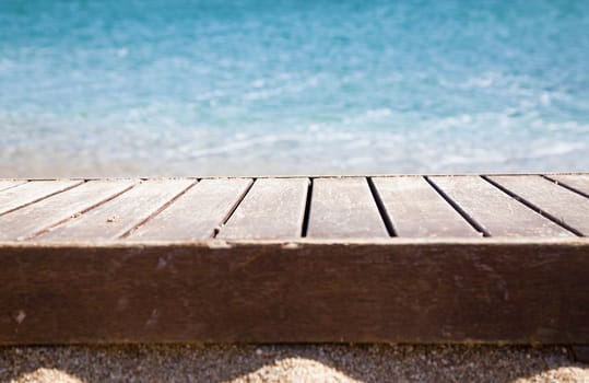 wooden plank in sand and blue sea in the background