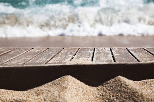 wooden plank in sand and blue sea in the background