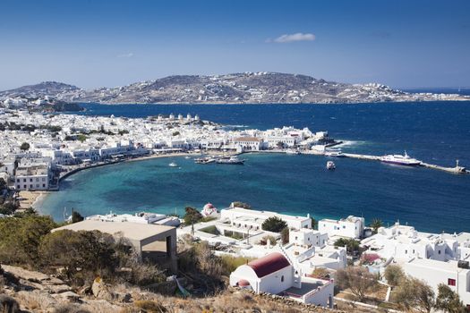 panoramic view of the Mykonos town harbor with famous windmills from the above hills on a sunny summer day, Mykonos, Cyclades, Greece