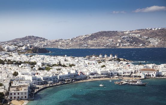 panoramic view of the Mykonos town harbor with famous windmills from the above hills on a sunny summer day, Mykonos, Cyclades, Greece