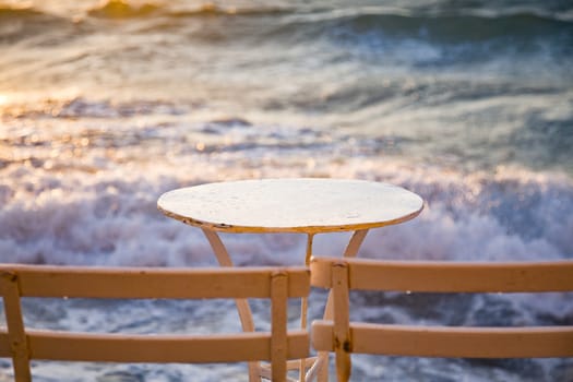table and chairs near the waves at sunset - beach holiday