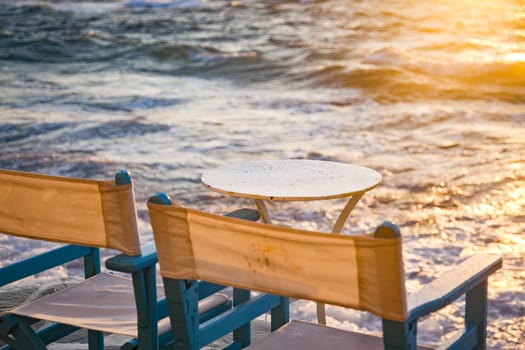 table and chairs near the waves at sunset - beach holiday