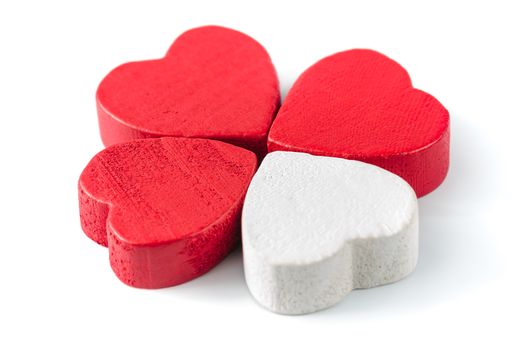 Four wooden roughly carved hearts, three red and white one, isolated on white, looks like four-leaf clover