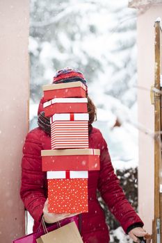 woman returning home from shopping holding pile of christmas present boxes 