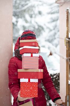 woman returning home from shopping holding pile of christmas present boxes 